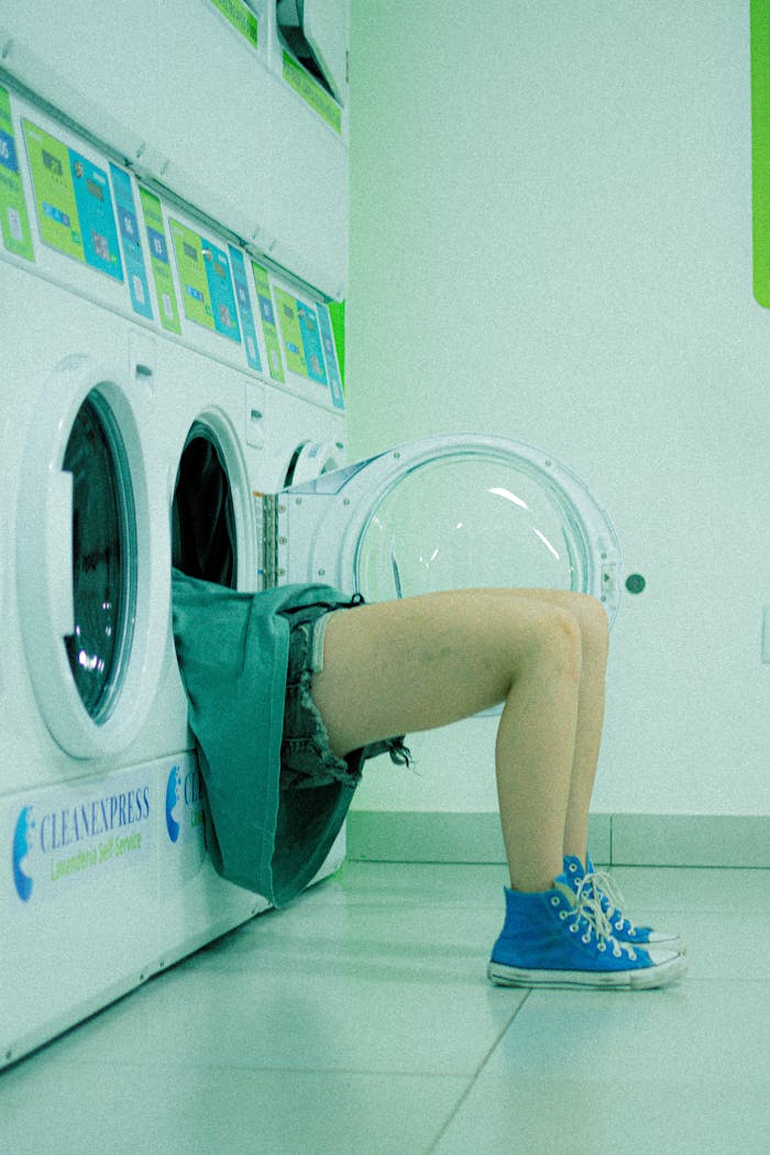 Humorous image of a person partially inside a washing machine at a laundromat.